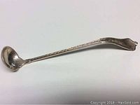Full length view of the antique sterling silver dipper spoon showing the bowl and engraved handle.