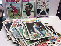 Pile of baseball cards featuring various players from different teams mostly from the 1970s, showing front sides with players in mid-action or portrait shots.