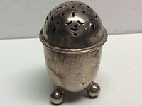 Front view of silver footed shaker with dome perforated lid and three ball feet