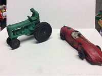 Side by side view of the green tractor and red race car rubber toys showing overall size, condition, and details.