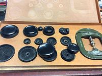 Early set of black watch repair tools and green metal clamp in a worn box