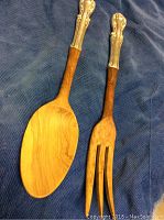 Sterling silver and teak rosewood salad fork and spoon laid on blue fabric.