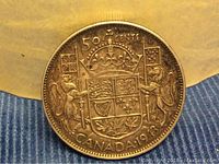 Close-up image of the reverse side of the 1943 Canadian silver half dollar coin showing the coat of arms and denomination.