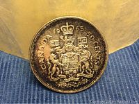 Obverse side of 1965 Canada Silver Half Dollar Coin showing details of coat of arms and inscription with natural patina and slight tarnish spots.