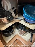Corner cabinet shelves with various pots, pans, bowls and strainer visible