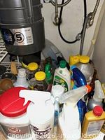 Under-sink area showing majority of cleaning bottles, wipes tub and sponges