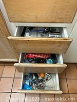 Three drawers open showing mixed kitchen tools