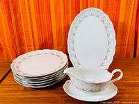 Stack of six dinner plates, oval platter, gravy boat on underplate