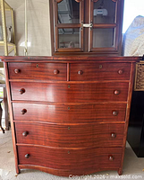 Front view showing six drawers, wood finish and knob hardware