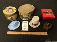 Overall lot view showing three miniature hats, three boxes and ruler for scale
