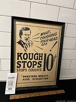Framed Kough Stops cough medicine advertising sign showing full design and attached ruler for scale
