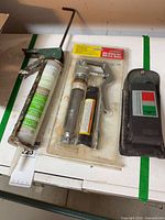 Overall view of moisture meter in case, packaged mini grease gun, and caulk gun with sealant tube