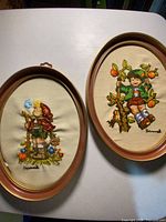Both oval framed embroideries side by side