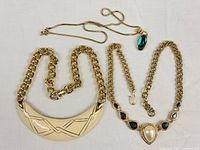 All three Monet necklaces laid out: crescent bib, pearl collar, green cabochon pendant