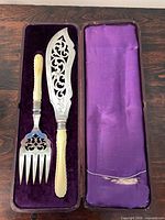 Fish slice and fork inside fitted box, velvet and satin lining visible