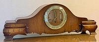 Front view of wooden mantel clock showing dial and case