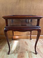Front view of wood and glass accent display table with cabriole legs