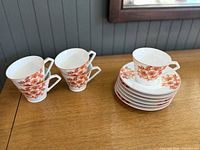 Three cups beside stack of saucers with one cup on top