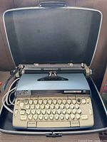 Typewriter in open carrying case, showing full keyboard and carriage