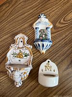 Front view of three ceramic holy water fonts on wood surface