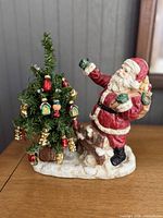 Santa figurine and decorated tree side by side on wood surface