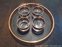 Top view of the round metal serving tray with four clear glass tumblers inside, each glass having a metallic band.