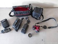 All items displayed: Nikon Coolpix camera, Hitachi camcorder, battery chargers, lens cap, carrying cases.