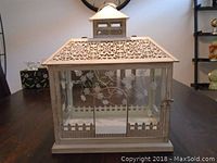 Front angle showing the metal lantern with decorative cutout roof and floral glass panels.