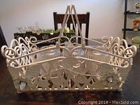 Front and top view of white metal basket with three glass candle holders inside.