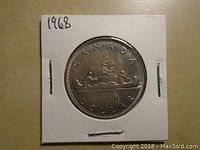 Reverse side of 1968 Canadian silver dollar coin showing canoe design with two paddlers and inscriptions