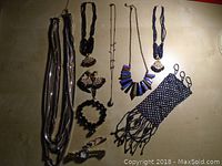 Multiple necklaces, bracelets, earrings, and a wristwatch laid on a surface showing the assortment of jewelry and accessories in the lot.