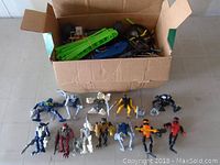 Box with 12 assorted action figures resembling robots and armored characters with varying colors and some articulation.