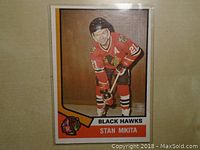 Front of a 1973-74 Stan Mikita hockey card showing the player in Chicago Black Hawks red uniform with number 21 and team logo.