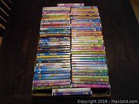 Photo showing stacked DVDs of kids movies and TV shows on a dark surface, multiple rows of varied colorful DVD cases.