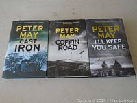 Front covers of three hardcover novels by Peter May: Cast Iron, Coffin Road, I'll Keep You Safe with dust jackets.