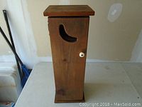 Small pine cabinet viewed from front side showing door with crescent cutout and white knob.