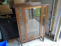 Front view of wooden china cabinet with central glass door and carved side panels