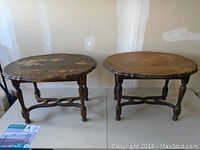 Pair of vintage solid wood end tables with oval scalloped tops and turned legs, showing wear and surface damage.