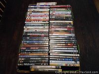 Stack of DVDs showing a wide range of movie titles and genres, arranged on a dark wooden surface.