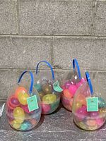 front view of four egg-shaped containers showing multicolor eggs and blue handles