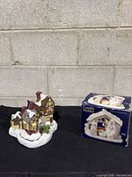 village house figurine beside boxed nativity candle holder