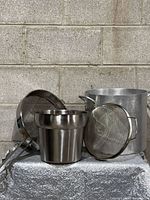 All four items grouped: stockpot, conical strainer, pail, sieve