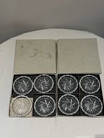 Open boxes showing eight coasters arranged in compartments