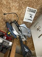 Overall view of Murana sliding compound miter saw mounted on base, manual visible