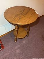 Full view of side table front showing round top, turned legs, lower shelf