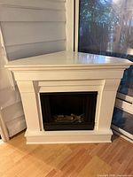 White corner fireplace showing mantel, firebox and triangular top