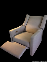 Front angled view showing wingback design, extended footrest, control panel on arm