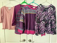 Four sweaters hung side by side showing full fronts and colours