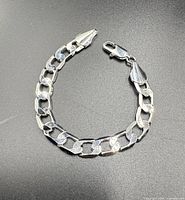 Full view of sterling silver Figaro link bracelet laid flat