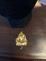 Front view of gold-tone leaf brooch showing blue rhinestones